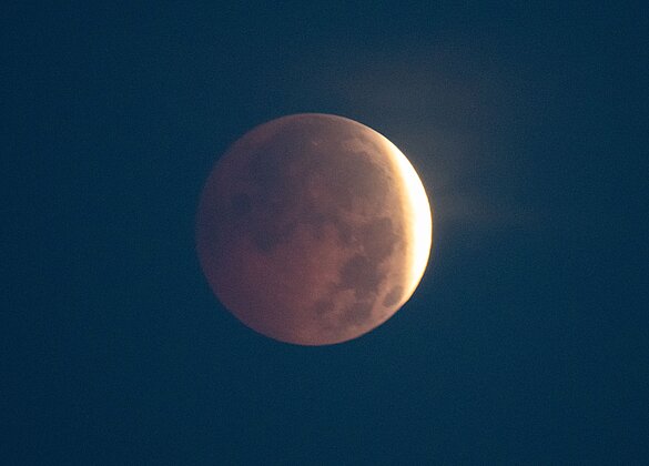 Eine Wolkenlücke gibt den Blick frei auf die Mondfinsternis.